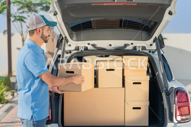 خدمة العملاء وعملية توصيل الطلبات للزبائن , شاب عربي اماراتي خليجي يرتدي لباس كاجوال وقبعة يعمل بتوصيل البضائع ويقوم بوضع الطلبات في صندوق السيارة , خدمة توصيل  وشحن الطلبات السريعة والموثوقة, التسوق الالكتروني تسوق ذكي