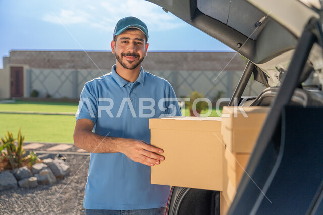 Customer service to deliver orders to customers, high-quality shipping and delivery, an Arab Gulf Emirati young man wearing a casual outfit, holding a cardboard box in his hand and looking at the camera with an expression of pleasure, safe and fast shipping operations in the Emirates