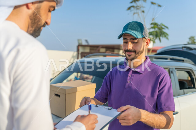 خدمات الشحن والتوصيل ذات الجودة العالية, توصيل طلبيات الاونلاين السريع, مندوب توصيل يرتدي لبس كاجوال يقف مع العميل بجانب سيارة شحن البضائع بتعابير السرور, التوقيع على أوراق تسليم واستلام المشتريات