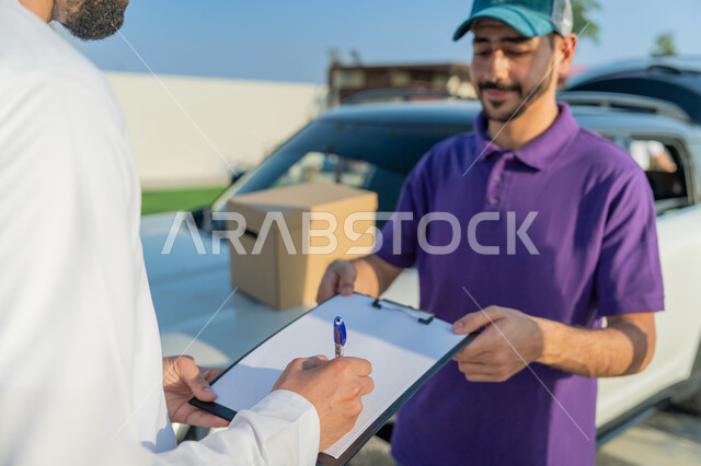 خدمة الديلفري الآمنة, توصيل طلبيات الاونلاين السريع, مندوب توصيل يرتدي لبس كاجوال يقف مع العميل بجانب سيارة شحن البضائع بتعابير السرور, التوقيع على أوراق تسليم واستلام المشتريات