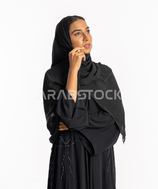 محاولة إيجاد حل لمشكلة ما، التمعن والتركيز والتخطيط للمستقبل، بورتريه لإمرأة عربية خليجية اماراتية محجبة ترتدي عباءة سوداء تضع يدها على ذقنها وتنظر بإيماءات التفكير والتأمل، شابة سعودية أنيقة، خلفية بيضاء