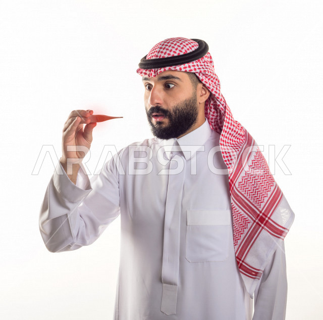 بورتريه لشاب سعودي خليجي يعاني من حمى شديدة ، ،ارتفاع درجات الحرارة ، جهاز قياس درجات الحرارة ، حالة مرضية ،  خلفية بيضاء