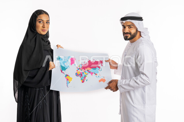 تحديد مسار سير الرحلة، البحث والاستكشاف حول العالم، مفهوم السياحة والسفر، القيام بجولات سياحية ترفيهية، بورتريه من الجانب لزوجين عربيين خليجيين اماراتيين يحملان بيدهما الخريطة، الاستعداد لقضاء رحلة صيفية ممتعة، خلفية بيضاء