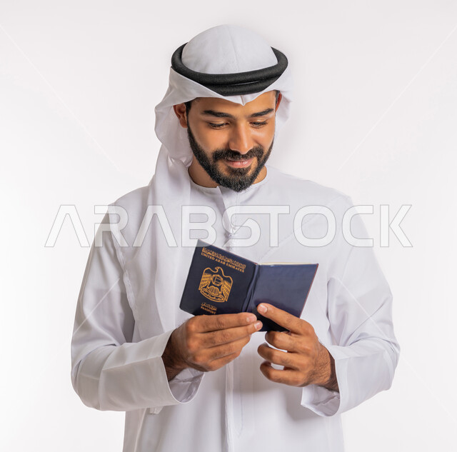 تأشيرة سفر دولية، إيماءات السرور والفرح، مفهوم السياحة والسفر، شعار دولة الامارات العربية المتحدة، بورتريه مقرب لرجل عربي خليجي اماراتي يرتدي الكندورة والغترة ينظر إلى الباسبور بتعابير البهجة والسرور، خلفية بيضاء