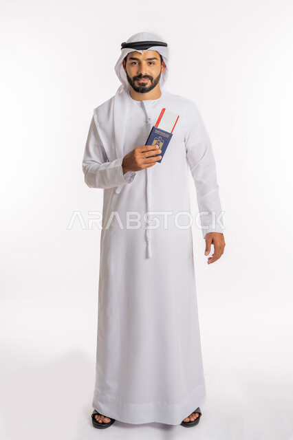 مفهوم السياحة والسفر، تعابير البهجة والسرور، إيماءات الفرح والسعادة، تأشيرة سفر دولية، شعار دولة الامارات العربية المتحدة، بورتريه لرجل عربي خليجي اماراتي يرتدي الكندورة والغترة يحمل بيده الباسبور وتيكت الطيارة، صورة لكامل الجسم، خلفية بيضاء