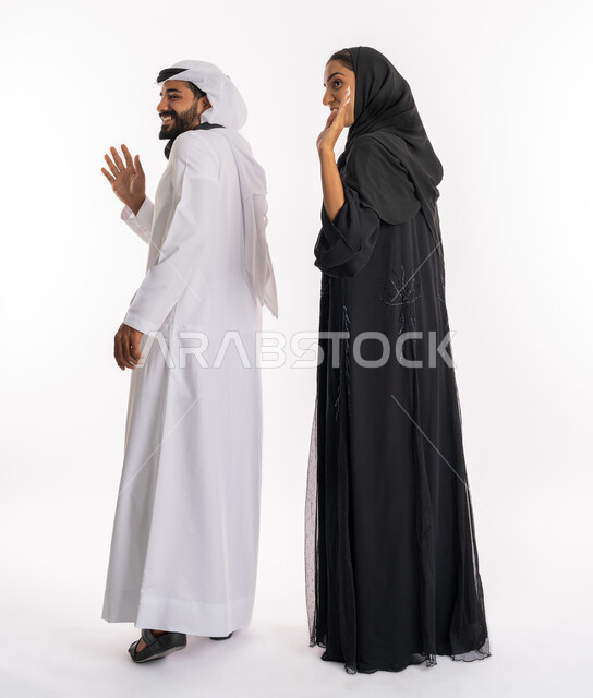 مفهوم الأسرة السعيدة، تعابير إلقاء التحية والسلام، بورتريه من الجانب لزوجان عربيين خليجيين اماراتيين يقومان برفع يديهم بايماءات الترحيب والاستقبال، قضاء زيارات عائلية ممتعة، صورة لكامل الجسم، خلفية بيضاء