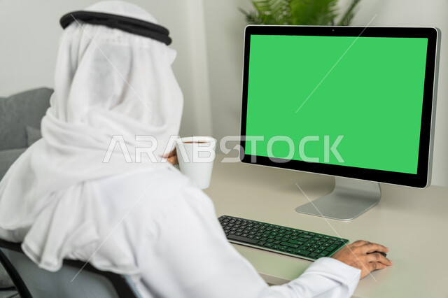 Chat, conversations, and social networking, marketing a website, using a desktop computer with a green chroma background, a picture from behind of an Arab Gulf Emirati man wearing a kandora and a white ghutra, drinking coffee, making a video call, watching movies and series.