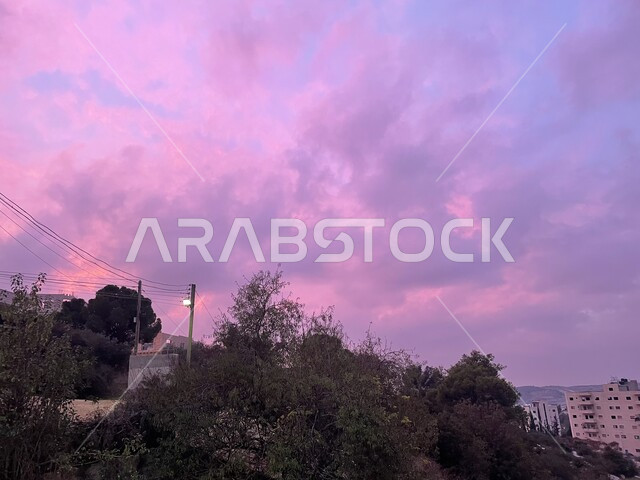 A view of the sky full of clouds, agricultural terraces in Palestine, green plants and trees on the slopes of the mountains, houses and residential buildings on the mountain peaks and heights, nature background