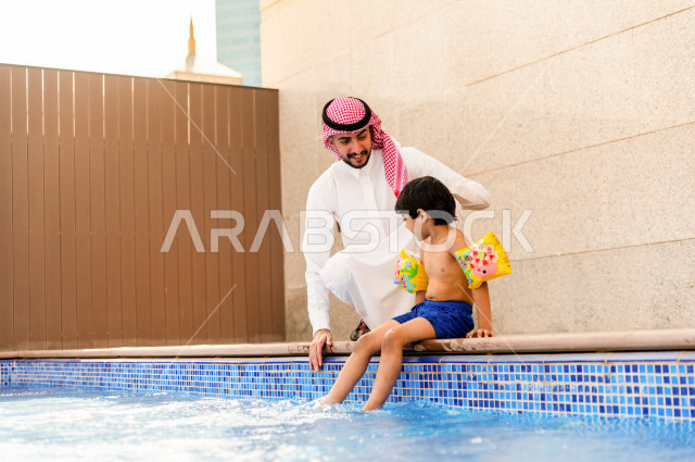 أب سعودي عربي يعلم ابنه مهارة السباحة , السباحة والغوص في أفضل المنتجعات السياحية , الاستجمام و الاسترخاء في عطلة الصيف . 