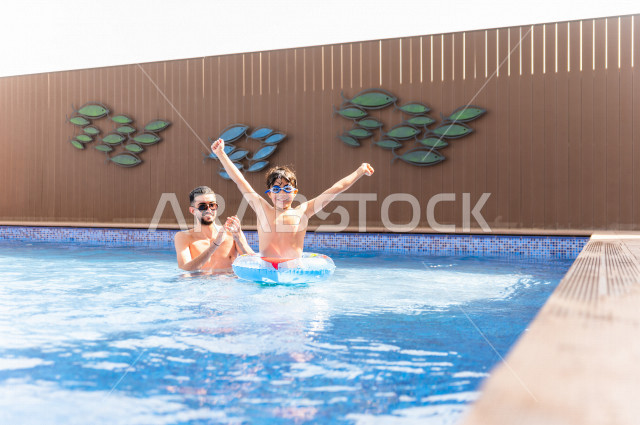 أب سعودي عربي يعلم ابنه مهارة السباحة , السباحة والغوص في أفضل المنتجعات السياحية , الاستجمام و الاسترخاء في عطلة الصيف . 