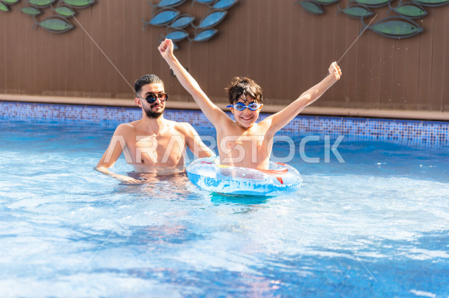 أب سعودي عربي يعلم ابنه مهارة السباحة , السباحة والغوص في أفضل المنتجعات السياحية , الاستجمام و الاسترخاء في عطلة الصيف . 