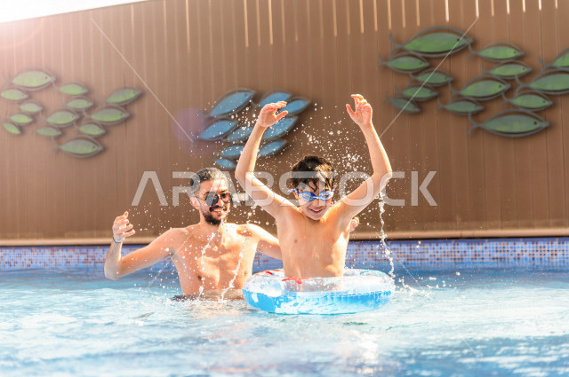 أب سعودي عربي يعلم ابنه مهارة السباحة , السباحة والغوص في أفضل المنتجعات السياحية , الاستجمام و الاسترخاء في عطلة الصيف . 