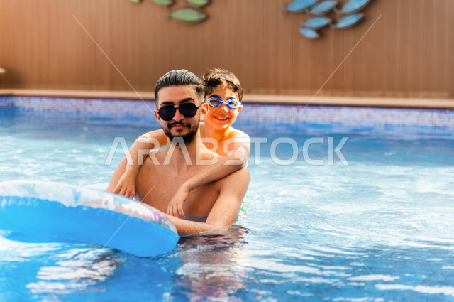 أب سعودي عربي يعلم ابنه مهارة السباحة , السباحة والغوص في أفضل المنتجعات السياحية , الاستجمام و الاسترخاء في عطلة الصيف . 