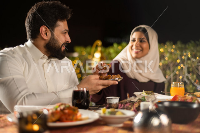 A Saudi Arabian couple at the breakfast table in the month of Ramadan, sharing the wonderful atmosphere of Ramadan in the open air, a trip filled with varieties of delicious Saudi Arabian food, the month of Ramadan, Ramadan Kareem, Ramadan Lantern