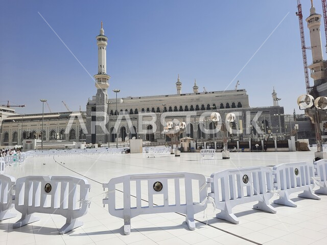 أداء مناسك الحج والعمرة، الحجاج والمعتمرين في الساحة الخارجية للمسجد الحرام في مكة المكرمة في النهار، معالم دينية إسلامية في المملكة العربية السعودية، الفن الهندسي المعماري على الطراز الإسلامي للأبراج المحيطة بالحرم المكي الشريف