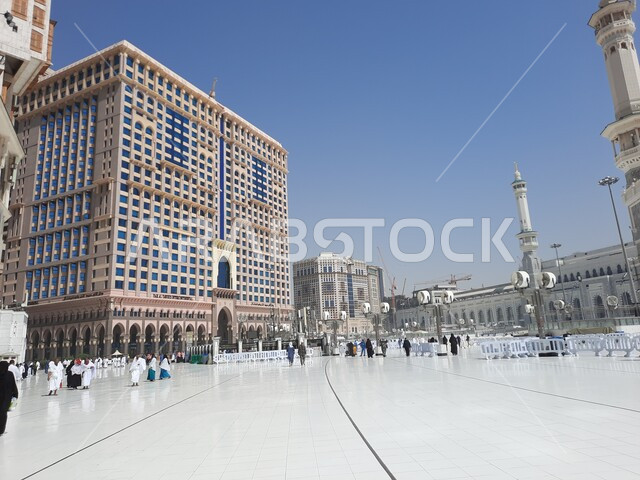 Islamic architectural engineering art of the towers surrounding the Holy Mosque of Mecca, performing Hajj and Umrah rituals, pilgrims and pilgrims in the outer courtyard of the Grand Mosque in Mecca during the day, Islamic religious landmarks in the Kingdom of Saudi Arabia