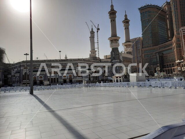 الفن الهندسي المعماري على الطراز الإسلامي للأبراج المحيطة بالحرم المكي الشريف، أداء مناسك الحج والعمرة، الحجاج والمعتمرين في الساحة الخارجية للمسجد الحرام في مكة المكرمة في النهار، معالم دينية إسلامية في المملكة العربية السعودية