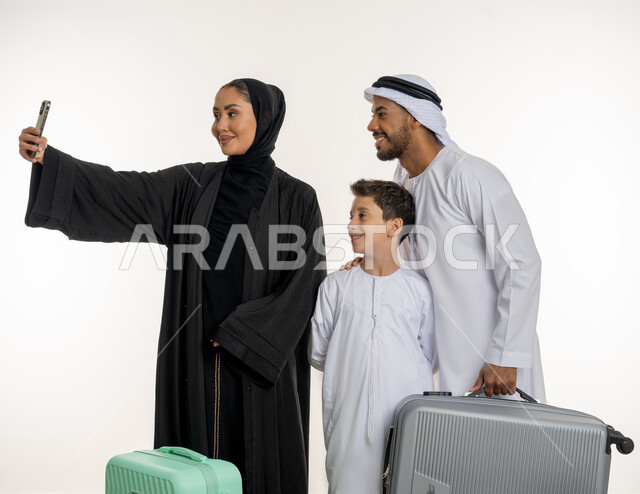 السفر والذهاب برحلات ممتعة, بورتريه لعائلة عربية خليجية إماراتية تستعد للذهاب برحلة جديدة, التقاط صور سيلفي عبر الهاتف المحمول, تصوير الذكريات الجمبلة, سياحة و سفر في الامارات، أوقات مميزة مع الأسرة، خلفية بيضاء
