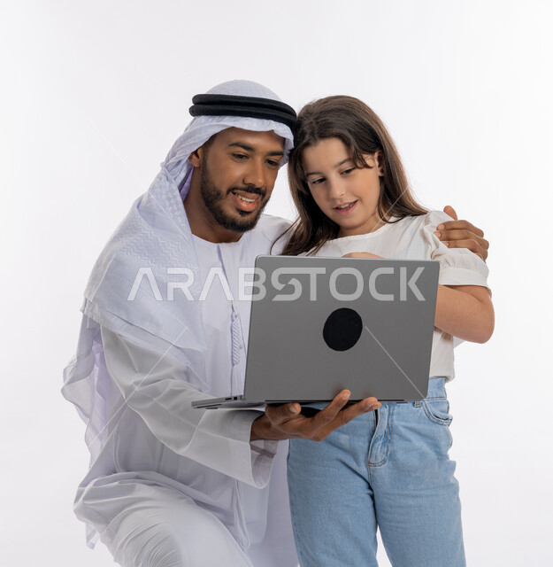 مفهوم التعلم عن بعد باستخدام الأجهزة التقنية الحديثة والتكنولوجيا، بورتريه لعائلة عربية خليجية إماراتية تجلس أمام الحاسوب المحمول, أب وابنته يقومون بمتابعة الدروس أونلاين، زي إماراتي كندورة وغترة، مساعدة الأبناء في حل الواجبات الدراسية، خلفية بيضاء