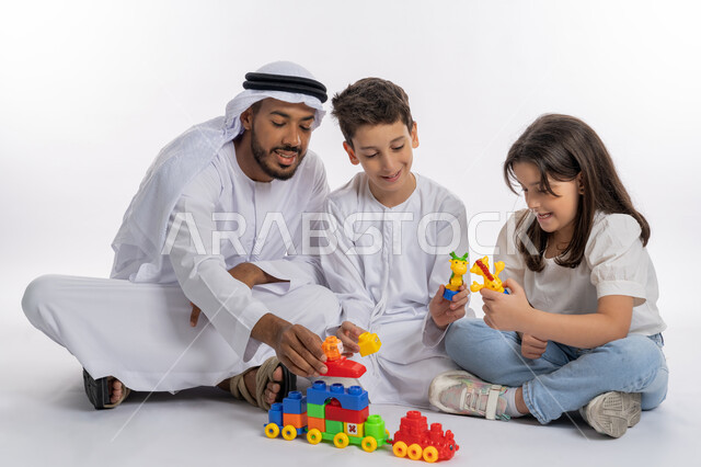 Sharing leisure time with children, a portrait of an Arab Gulf Emirati family spending an enjoyable time, a father wearing the Emirati kandora and ghutra playing with his children, gestures of joy and happiness, the importance of playing with children, the concept of a happy Emirati family, white background