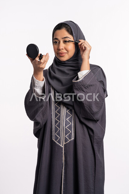 إبراز جمال العينين، مفهوم الإهتمام بالجمال والبشرة والمظهر الخارجي، دورات تعليمية لمكياج تتوريال, خبيرة سعودية لمستحضرات التجميل النسائية، بورتريه مقرب لإمرأة عربية خليجية إماراتية ترتدي العباءة والحجاب تحمل قلم الكحل الأسود، خلفيه بيضاء