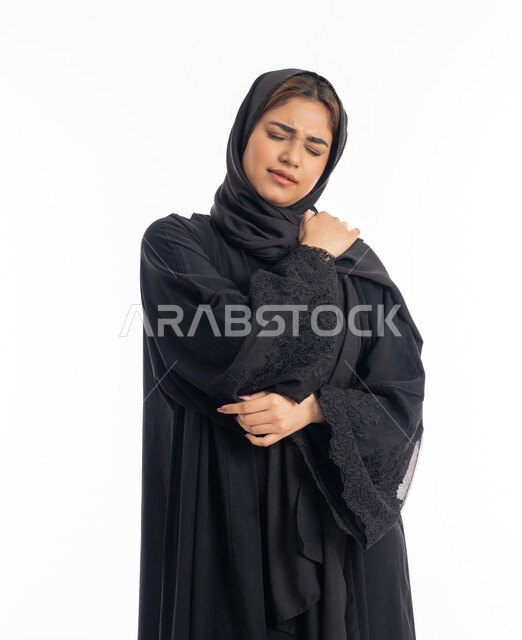 الاحساس بالمرض والتعب، التهاب العضلات والمفاصل، الحاجه للعلاج وطلب المساعده، بورتريه مقرب لامرأة عربيه خليجيه إماراتية ترتدي العباءة السوداء، سيدة سعودية تضع يدها على كتفها بإيماءات تدل على الألم، خلفية بيضاء