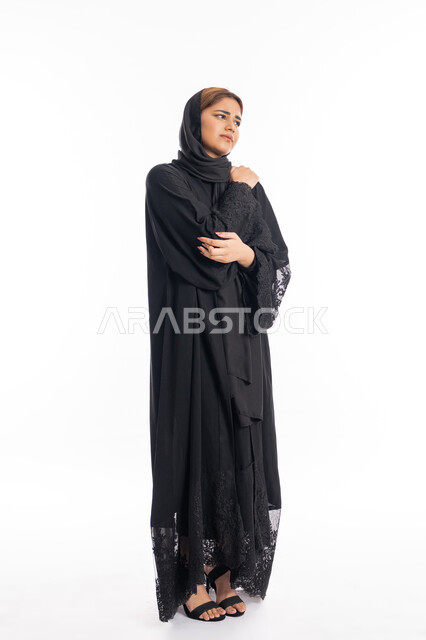 التهاب العضلات والمفاصل، الحاجه للعلاج وطلب المساعده، الإحساس بالمرض والتعب،  بورتريه لامرأة عربيه خليجيه إماراتية ترتدي العباءة السوداء، سيدة سعودية تضع يدها على كتفها بإيماءات تدل على الألم، الجسم بالطول الكامل، خلفية بيضاء
