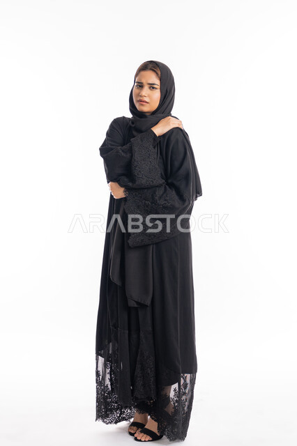 الحاجه للعلاج وطلب المساعده، التهاب العضلات والمفاصل، الإحساس بالمرض والتعب،  بورتريه لامرأة عربيه خليجيه إماراتية ترتدي العباءة السوداء، سيدة سعودية تضع يدها على كتفها بإيماءات تدل على الألم، الجسم بالطول الكامل، خلفية بيضاء