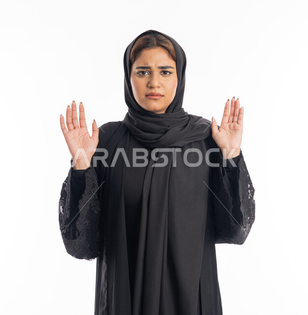 القلق والاحتياط والابتعاد عن شيء ما، رفع اليدين بإيماءات التوقف وعدم الاقتراب، حماية النفس من ضرر خارجي, سيدة عربية إماراتية ترتدي العباءة السوداء، بورتريه مقرب لامرأه خليجيه سعوديه تقف بحذر وذعر ورهبة،  خلفية بيضاء