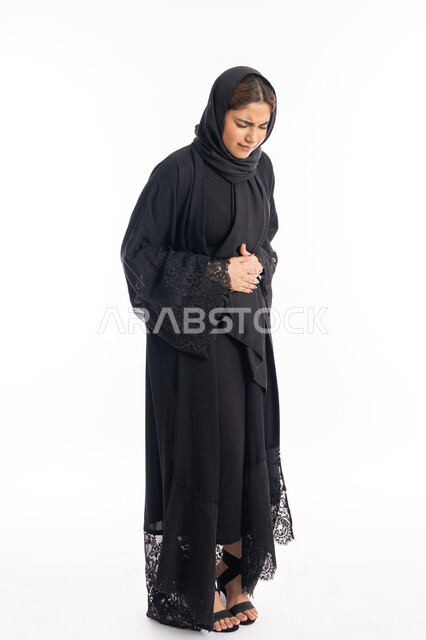 الإحساس بالمغص والوجع، إيماءات التقيؤ والغثيان، الحاجه للمساعدة وطلب العلاج، الشعور بحرقة في المعدة وعسر الهضم،  سيدة عربية إماراتية ترتدي العباءة السوداء، بورتريه لامرأه خليجيه سعوديه تضع يدها على بطنها تنحني من شدة الألم، الجسم بالطول الكامل، خلفية بيضاء