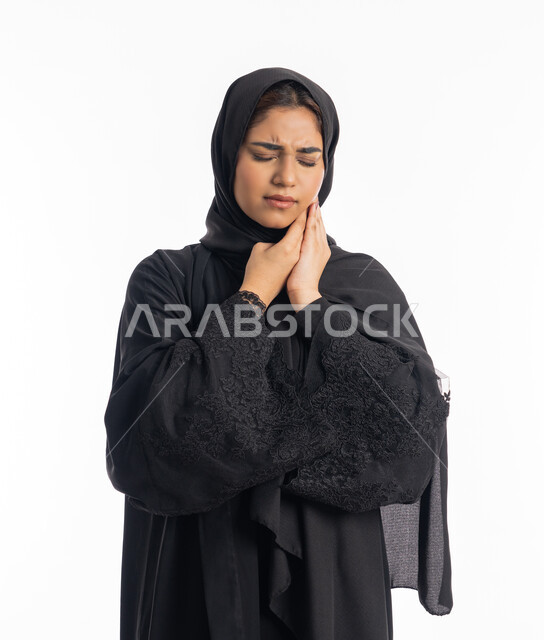 تعابير وجع اللثه وتسوس الأضراس، طلب العلاج و المساعده، الحاجه لزيارة الطبيب، سيدة عربية إماراتية ترتدي العباءة السوداء، بورتريه مقرب لامرأه خليجيه سعوديه محجبة تضع يدها على خدها بإيماءات الشعور بألم الأسنان، خلفية بيضاء