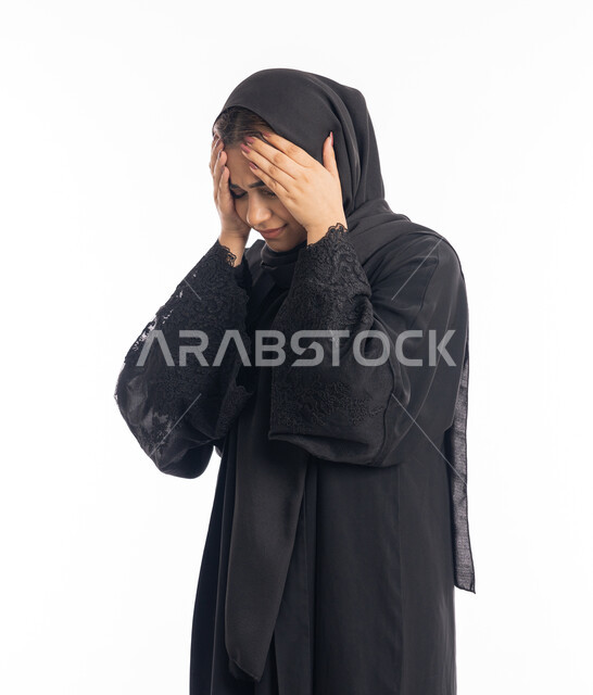 الحاجة إلى العلاج والمساعده، الشعور بألم الرأس والصداع، المعاناة من آلام الشقيقة، الحاجة للهدوء والراحة، بورتريه مقرب لإمرأة خليجية سعودية محجبة تضع يديها على رأسها بايماءات التعب والارهاق، سيدة عربية إماراتية ترتدي العباءة السوداء، خلفية بيضاء