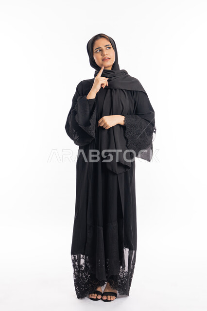 التمعن والتركيز والتخطيط للمستقبل، إيماءات الحيرة والقلق, محاولة إيجاد حل لشيء ما, بورتريه   لامرأه خليجيه سعوديه محجبة تضع يدها على ذقنها وتنظر بعيداً بتفكير وتأمل، النظر بشرود إلى مكان ما, سيدة عربية إماراتية ترتدي العباءة السوداء، الجسم بالطول الكامل، خلفية بيضاء