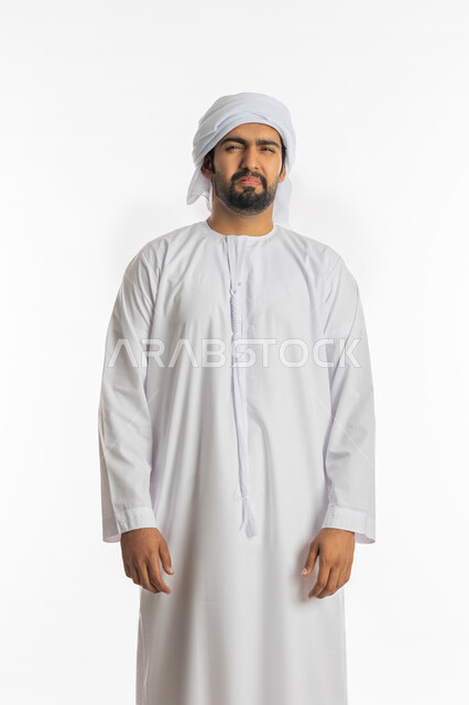 الشعور بالحزن والضجر، تعابير الانزعاج والغضب، بورتريه لرجل عربي خليجي اماراتي يرتدي الكندورة الاماراتية والعمامة ينظر إلى الكاميرا بإيماءات التقزز والاسمزاز، الاهتمام بالمظهر الخارجي، خلفية بيضاء