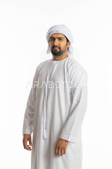 الاهتمام بالمظهر الخارجي، الشعور بالحزن والضجر، تعابير الانزعاج والغضب، بورتريه من الجانب لرجل عربي خليجي اماراتي يرتدي الكندورة الاماراتية والعمامة ينظر إلى الكاميرا بإيماءات التقزز والاسمزاز، خلفية بيضاء