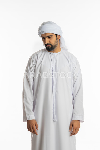 The concept of elegance, masculinity and strength, concern for external appearance, a portrait of an Emirati Gulf Arab man wearing the Emirati kandora and ghutra, looking over his shoulder with gestures of seriousness, expressions of self-confidence, white background.