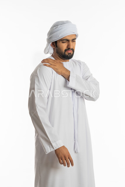 تعابير الألم و وجع الظهر، الحاجة للعلاج والاستشارة الطبية، الشعور بالمرض والإرهاق، بورتريه من الجانب لرجل عربي خليجي اماراتي يرتدي الكندورة الاماراتية والكندورة يضع يده على كتفه بايماءات التعب، خلفية بيضاء