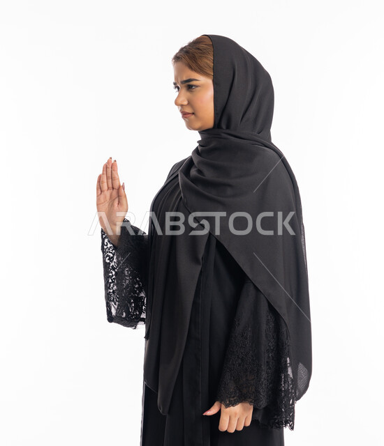 الشعور بالإنزعاج والغضب، تعابير الرفض والإمتناع، الأمر بالتوقف عن فعل شيء ما، بورتريه من الجانب لامرأه عربيه خليجيه اماراتية محجة ترتدي عباءة سوداء ترفع يدها بإيماءات تدل على النهي، شابة سعودية انيقة، خلفية بيضاء