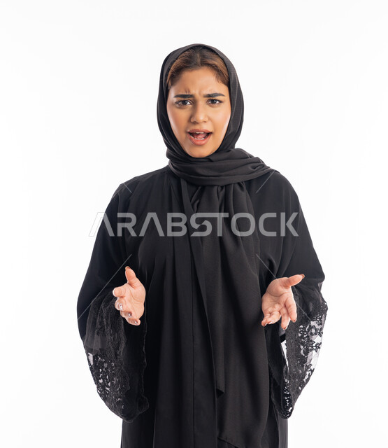 الانزعاج لسماع الأخبار السيئة، الشعور بالحزن والضجر، بورتريه لإمرأة عربية خليجية امارايتة محجبة ترتدي عباءة سوداء ترفع يديها بايماءات الصدمة، شابة سعودية انيقة، خلفية بيضاء