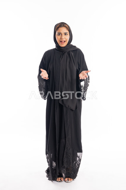 مفهوم الفرح بتحقيق شيء ما، سماع الاخبار والمفاجأت السعيدة، شابة سعودية انيقة، بورتريه لامرأة عربية خليجية اماراتية محجبة ترتدي عباءة سوداء ترفع يديها بإيماءات الدهشة والسرور، صورة لكامل الجسم، خلفية بيضاء