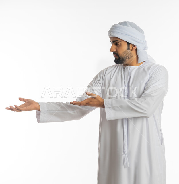 استخدام حاسة اللمس لتحريك العناصر الهولوجراميه، بورتريه لرجل عربي خليجي اماراتي يرتدي الكندورة الاماراتية والعمامة يشير الى يده، ايماءات حمل ورفع شيء ما، الإشارة نحو هدف معين، خلفية بيضاء