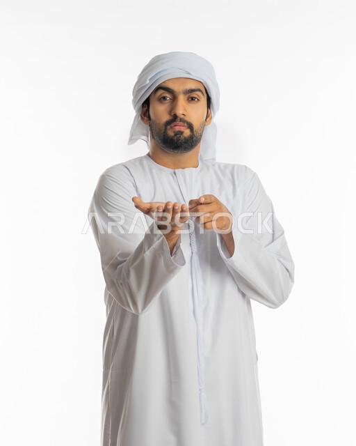 Gestures of carrying and lifting something, portrait of an Emirati Gulf Arab man wearing the Emirati kandora and white turban, pointing with the index finger of his hand, pointing towards a goal, movement of fingers and gestures, white background