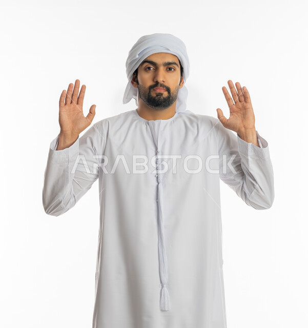 حماية النفس من ضرر خارجي, رفع اليدين بإيماءات التوقف وعدم الاقتراب, بورتريه مقرب لرجل عربي خليجي إماراتي يرتدي الكندورة والعمامة يقف بحذر وذعر ورهبة, القلق والاحتياط والابتعاد عن شيء ما, خلفية بيضاء