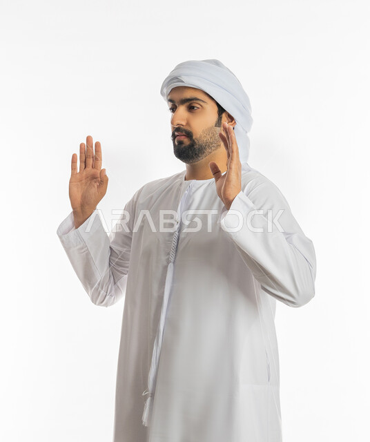 القلق والاحتياط والابتعاد عن شيء ما، رفع اليدين بإيماءات التوقف وعدم الاقتراب، حماية النفس من ضرر خارجي, بورتريه من الجانب لرجل عربي خليجي إماراتي يرتدي الكندورة والعمامة يقف بحذر وذعر ورهبة, خلفية بيضاء