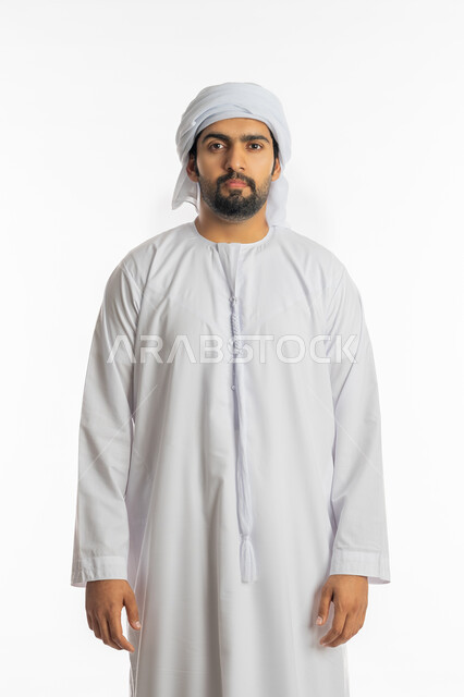 The concept of elegance, masculinity and strength, concern for external appearance, a portrait of an Emirati Gulf Arab man wearing the Emirati kandora and ghutra, standing straight and looking at the camera with gestures of self-confidence, white background.