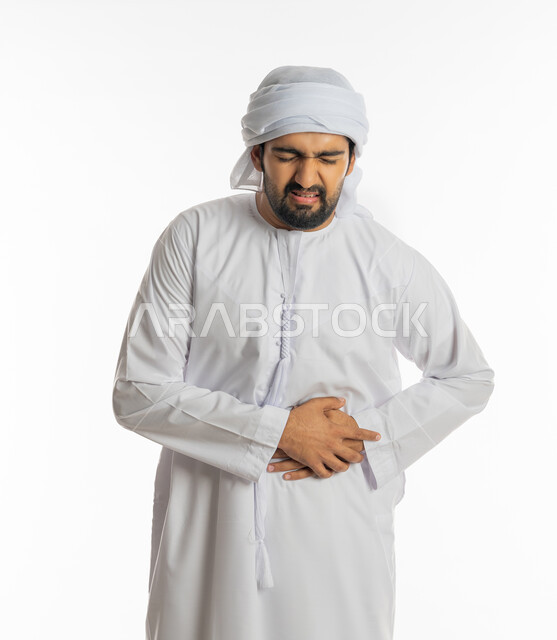 إيماءات التقيؤ والغثيان، الإحساس بالمغص والوجع، الحاجه للمساعدة وطلب العلاج، الشعور بحرقة في المعدة وعسر الهضم، بورتريه لرجل عربي خليجي اماراتي يرتدي الكندورة الاماراتية والعمامة البيضاء يضع يده على بطنه ينحني من شدة الألم، خلفية بيضاء