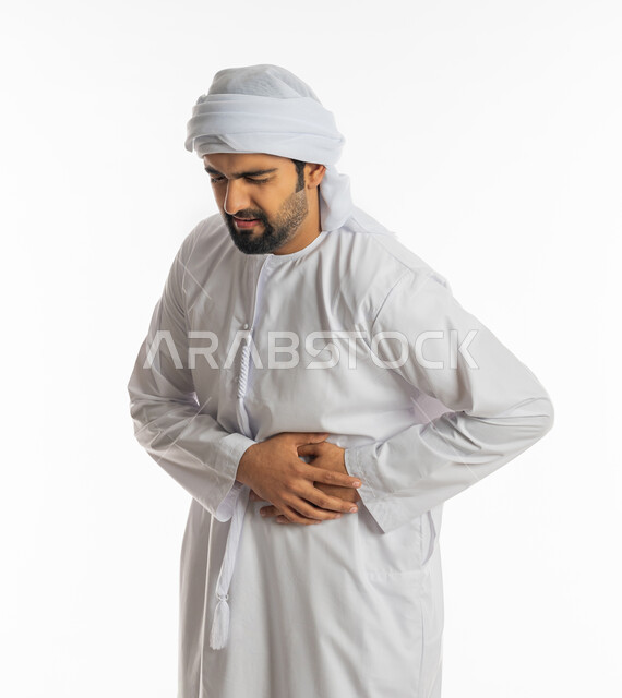 الشعور بحرقة في المعدة وعسر الهضم، الحاجه للمساعدة وطلب العلاج، الإحساس بالمغص والوجع، بورتريه لرجل عربي خليجي اماراتي يرتدي الكندورة الاماراتية والعمامة البيضاء يضع يده على بطنه ينحني من شدة الألم، إيماءات التقيؤ والغثيان، خلفية بيضاء