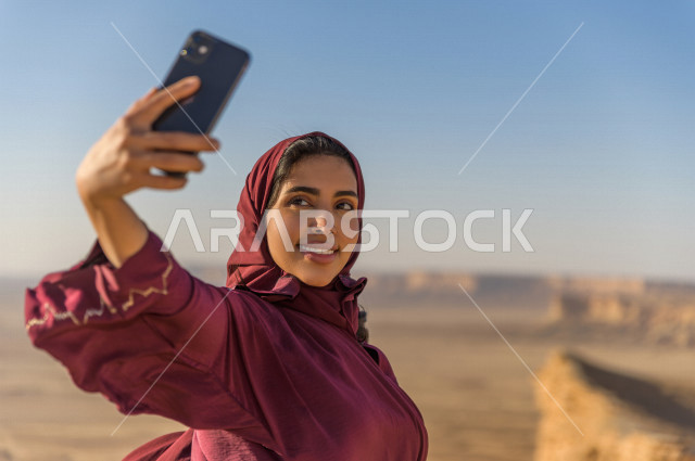 سائحة سعودية خليجية تزور الأماكن السياحية بالمملكة العربية السعودية  ، منطقة مطل نهاية العالم السياحة في الرياض  ، مصورة خليجية تحمل هاتفها المحمول ، تلتقط صور سلفي ، مناطق صحراوية ، جمال الطبيعة السعودية