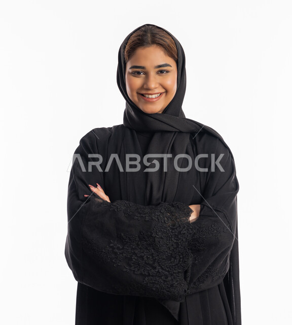 الاهتمام بالأناقة والاعتناء بالمظهر الخارجي، التقاط صور شخصية للوثائق الرسمية، سيدة سعودية مبتسمة تنظر الى الكاميرا بتعابير الأنوثة والنعومة, بورتريه مقرب لإمرأة عربية خليجية إماراتية ترتدي العباءة السوداء تقف بأيدي متقاطعة, خلفية بيضاء