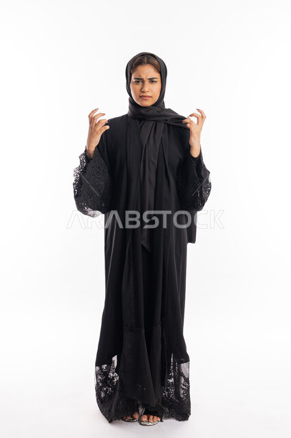 الحزن وطلب التوقف عن فعل الأخطاء, محاولة ضبط النفس وكتم الغضب, بورتريه لشابة عربية خليجية إماراتية ترتدي العباءة السوداء ترفع يديها بانزعاج, سيدة سعودية تقف بإيماءات العتاب والتوبيخ والرفض, صورة الجسم بالطول الكامل, خلفية بيضاء